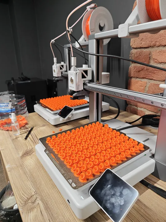 Печать партии оранжевых насадок из PETG, полные столы деталей